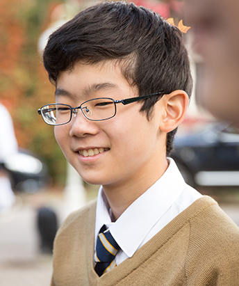 student wearing glasses and in a beige school jumper