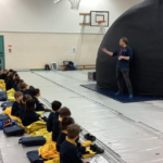 children sat down in front of a large dome