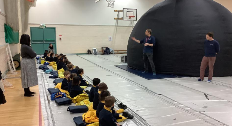 children sat down in front of a large dome